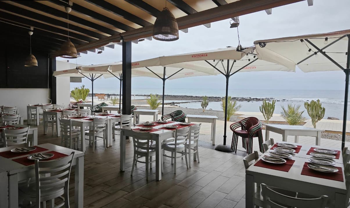 Terraza frente al mar de El Rinconcito de Doña Juanita, mesas preparadas bajo sombrillas con vistas al océano en Fuerteventura.