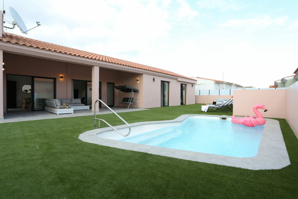 Piscina privada rodeada de césped artificial y porche amueblado