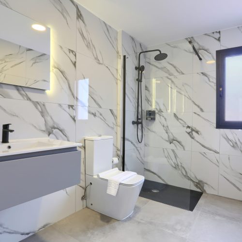 Baño moderno con revestimiento marmoleado y ducha a ras de suelo en Villa Gaudí