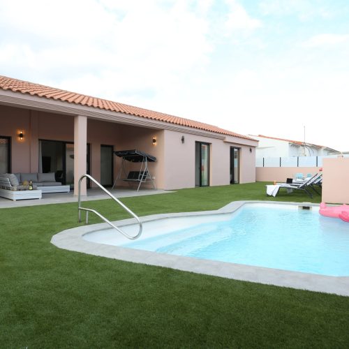 Piscina privada rodeada de césped artificial y porche amueblado