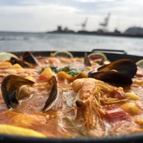 Paella de marisco con gambas, mejillones y limón junto al mar