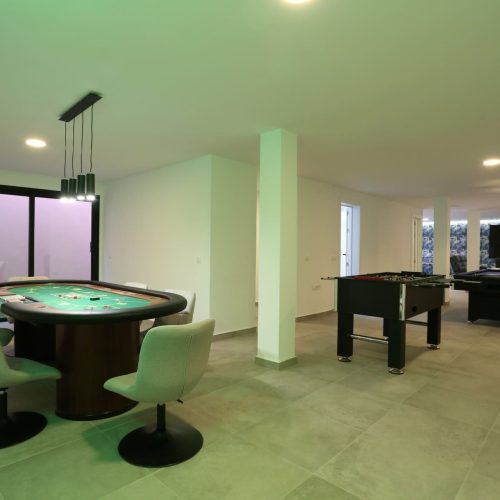 Sótano diáfano con mesa de póker, futbolín, billar y zona de TV en la villa
