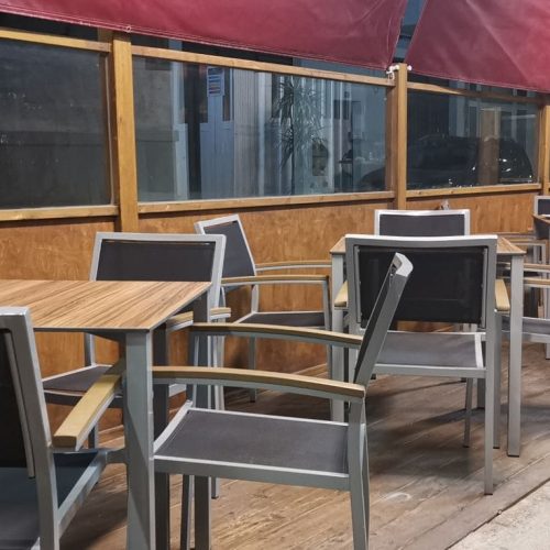 Terraza de La Puipana con mesas y sillas al aire libre bajo toldos rojos por la noche.